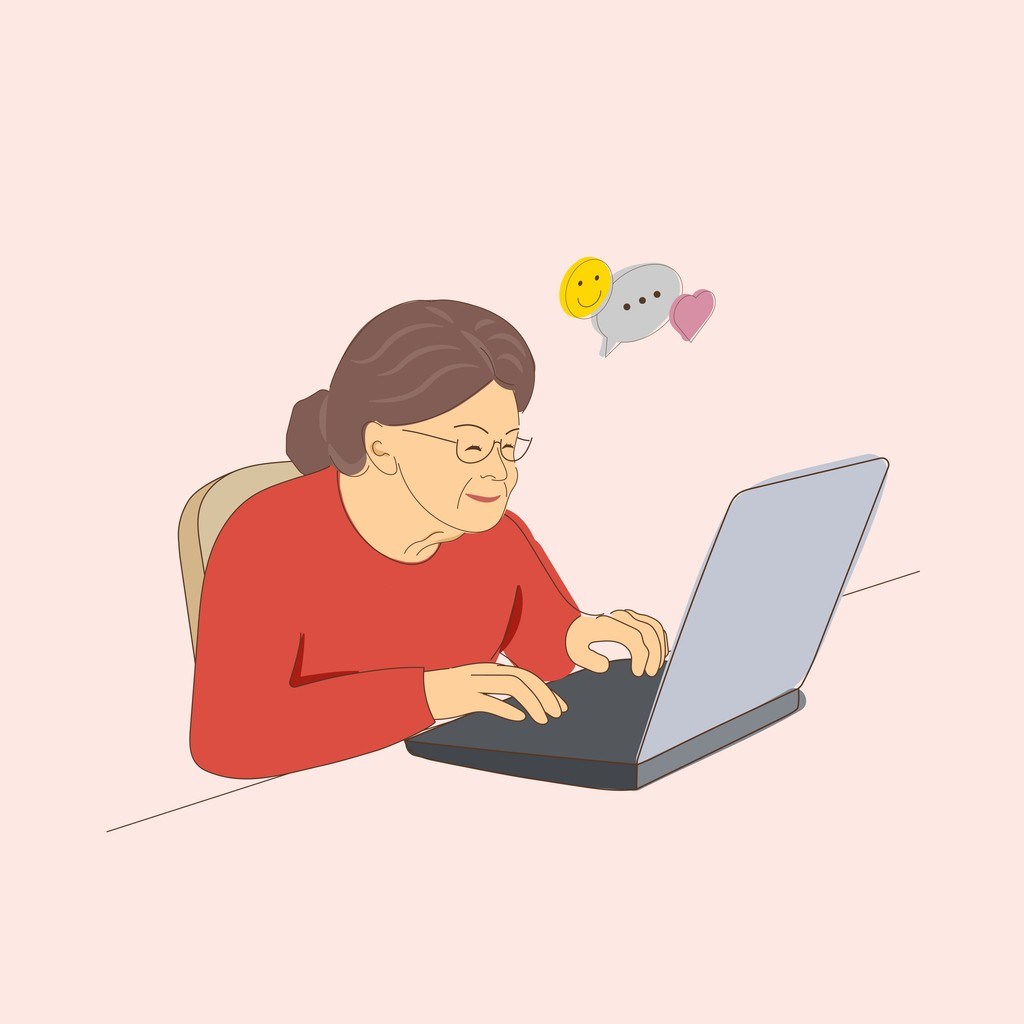 Eine ältere Dame lächelt, während sie einen Laptop benutzt