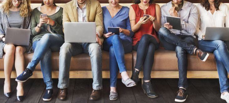 Menschen mit digitalen Geräten auf Sofa