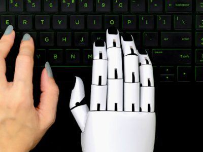 Eine menschliche und eine Roboterhand bedienen gemeinsam eine Tastatur