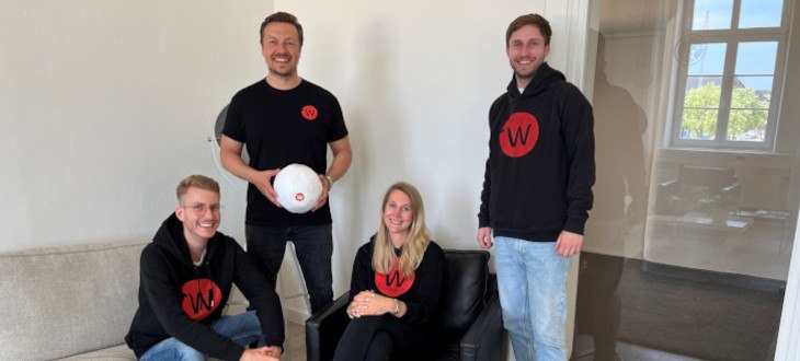 Das vierköpfige web-netz Team in Pullis mit web-netz Logo und Leiter Felix Benckendorff mit Fußball in der Hand